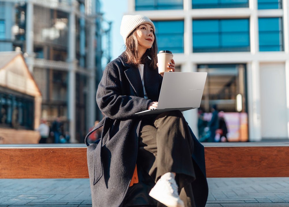 Young Asian female designer working with laptop while drinking coffee. Freelance work and flexible working. Distance learning and Online courses.